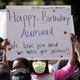 Woman holds up a sign wishing Ahmaud Arbery happy birthday at a protest in Brunswick, Ga.